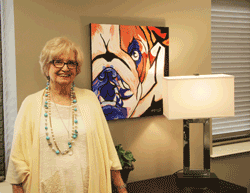 Inez Dickerson, an alumna of Holmes Community College, posing with one of her many paintings the walls of The Attala Center. Dickerson will teach a six-week Art class beginning Feb. 8 at The Attala Center.